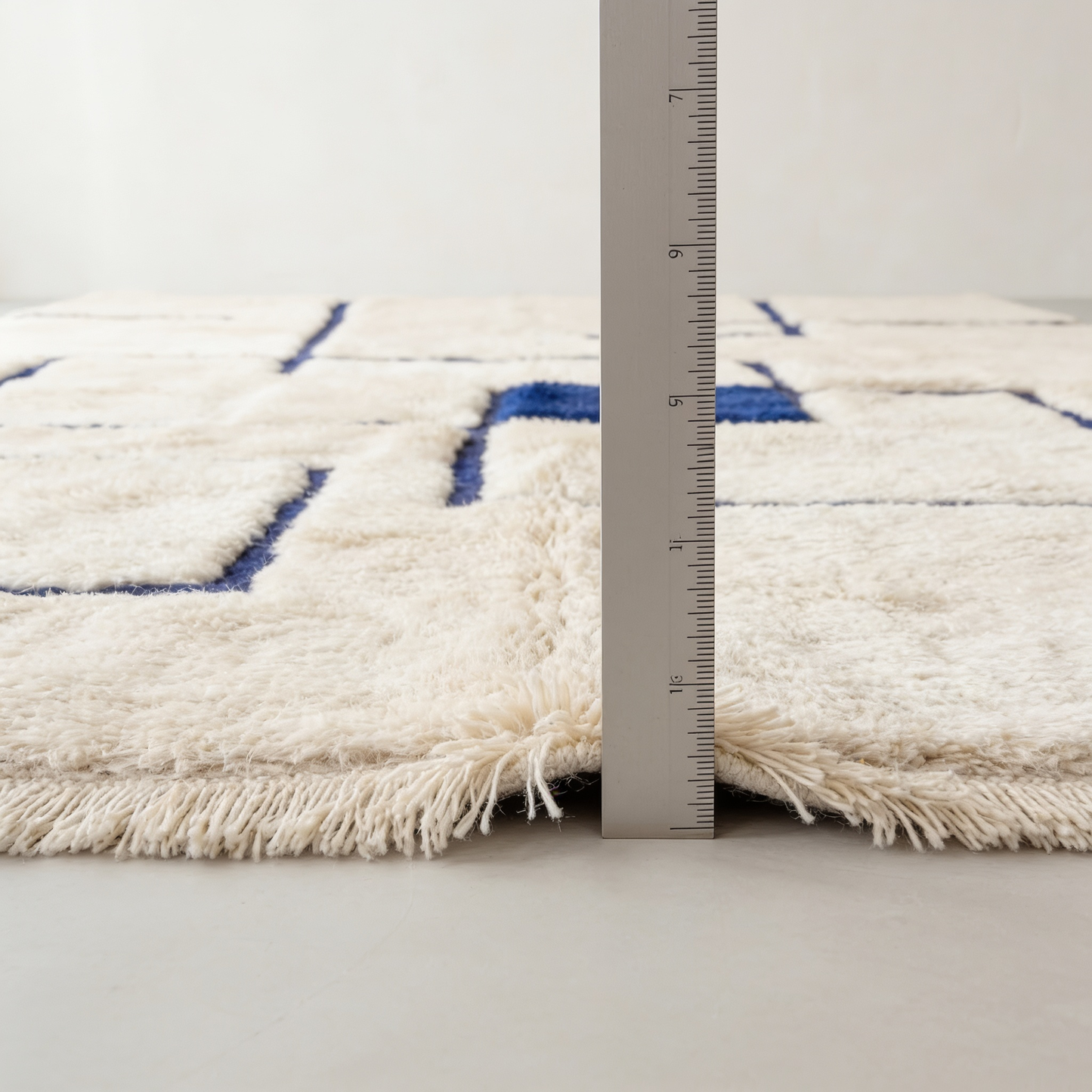 Tapis Berbère Mrirt écru à motifs bleus - mesure de l'épaisseur avec une règle graduée
