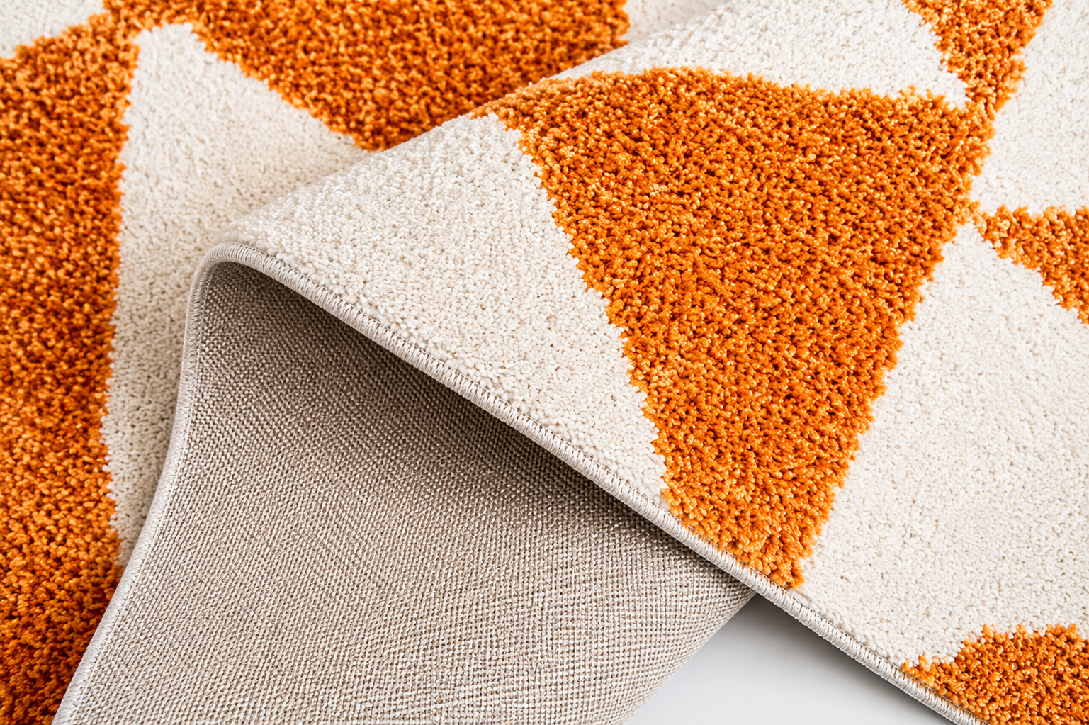 Détail de l'envers tissé plat beige et de la pile dense orange d'un tapis berbère géométrique